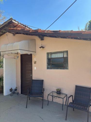 two chairs and a table in front of a house at Chalé Aconchegante Com Piscina e Ótima Localização in Serra Negra