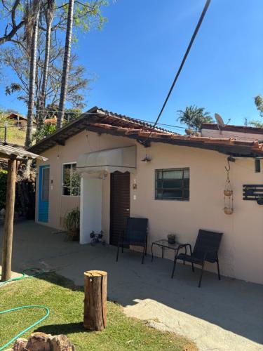 uma casa com duas cadeiras e uma mesa em frente em Kitnet Aconchegante Simples e Bem Localizada em Serra Negra