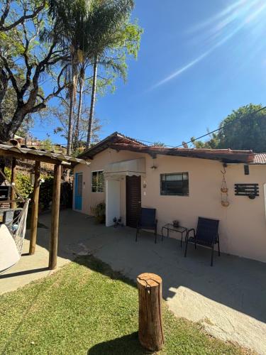 uma casa com duas cadeiras e uma mesa no quintal em Kitnet Aconchegante Simples e Bem Localizada em Serra Negra