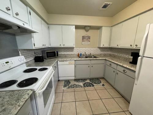 a kitchen with white appliances and a tile floor at No Checkout Work! NEW Family Friendly Stay! in College Station
