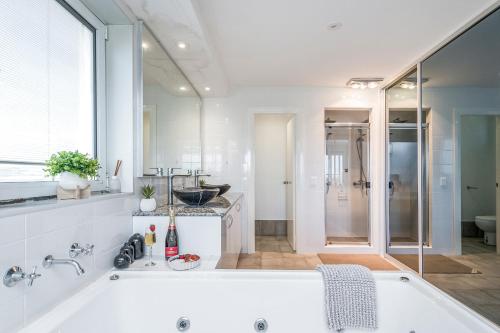 a white bathroom with a tub and a shower at Oceans Waves - Luxury Apartment with ocean views in Lancelin
