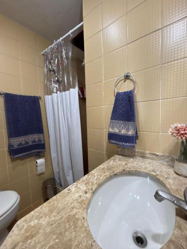 a bathroom with a sink and a toilet and blue towels at Le Corsaire in Búzios