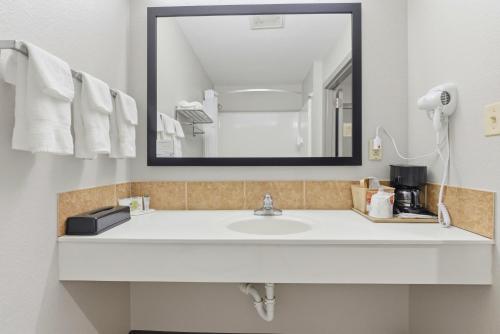 een badkamer met een witte wastafel en een spiegel bij Days Inn & Suites by Wyndham Wynne in Wynne