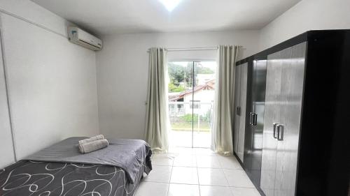 una camera da letto con un letto e una grande finestra di Casa Ampla com Ar Condicionado 450m praia Rua Canoas a Piçarras