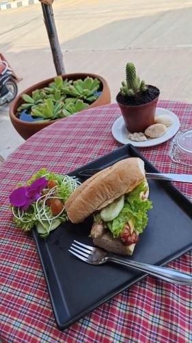 a sandwich and salad on a black plate on a table at The Sunshine hostel and hotel in Ko Lanta