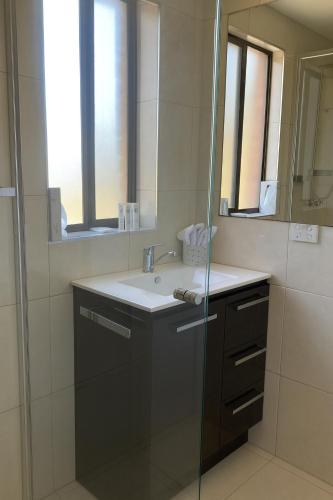 a bathroom with a sink and a glass shower at The Anchorage Bermagui in Bermagui