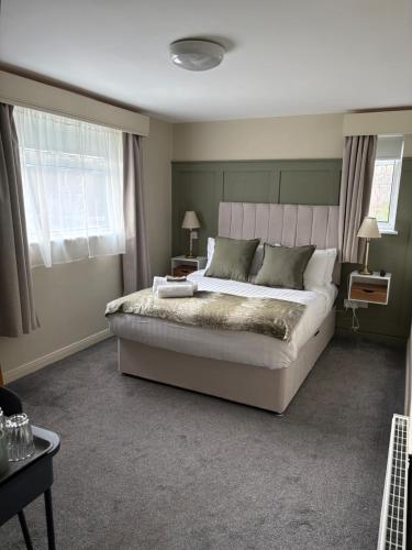 Un dormitorio con una cama grande y dos ventanas. en The Boutique Bungalow, en Bundoran