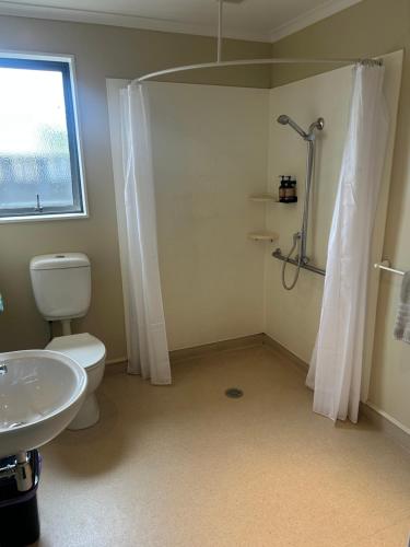 a bathroom with a shower and a toilet and a sink at Woodbourne Tavern and Motel in Renwick