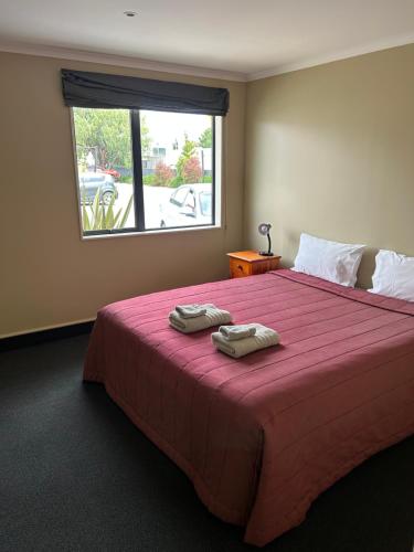 a bedroom with a large bed with two towels on it at Woodbourne Tavern and Motel in Renwick