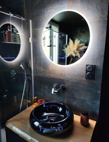 a bathroom with a black sink and a mirror at Cocon Romantique & Bain Nordique sur Vue Panoramique à Vichy in Vichy
