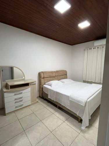 um quarto com uma cama, uma cómoda e uma televisão em Casa Aconchego Fóz em Foz do Iguaçu