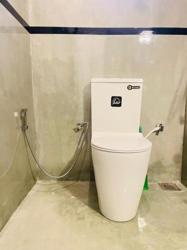 a white toilet in a bathroom with a hose at Tropictide Weligama in Weligama