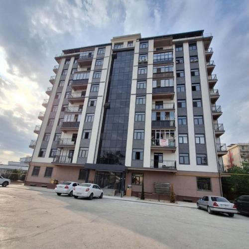 a large building with cars parked in front of it at Уютный Апартамент Новостройка 舒适公寓 in Tashkent