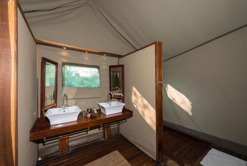 a bathroom with two sinks and a mirror at Ongava Tented Camp in Okaukuejo
