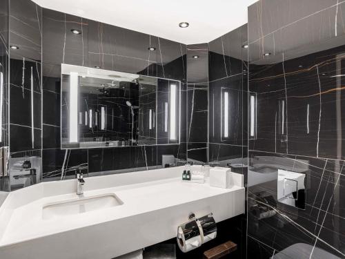 ein Badezimmer mit Waschbecken und Spiegel in der Unterkunft Sofitel London Gatwick in Horley