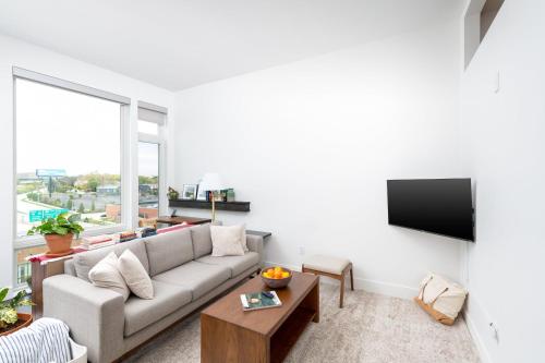 Una sala de estar con un sofá y un televisor de pantalla plana. en Modern 1BR Apt with Skywalk to Fiserv, Rooftop, and Parking, en Milwaukee