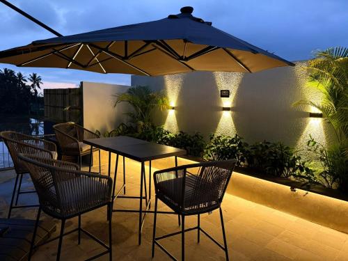 een patio met een tafel en stoelen onder een parasol bij Sava Villa Ubud Rice Fields View in Tegalalang