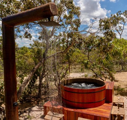a wooden hot tub in the middle of a field at Chales Estrela Veadeiros Com Ofurô in Alto Paraíso de Goiás