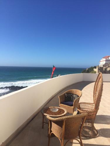 a balcony with chairs and a table and the ocean at Residencial Real Guest House in Sintra