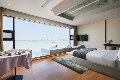 1 dormitorio con bañera, 1 cama y ventana grande en Floral Luxury Wuhu Lake Art Hotel, en Wuhu