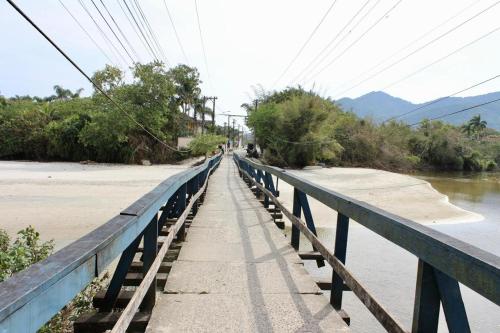 a bridge over a river with people walking on it at Casa em Juquehy 200m da praia in São Sebastião