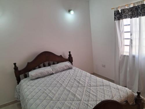 ein Schlafzimmer mit einem Bett mit Bettdecke und einem Fenster in der Unterkunft Casa mar del tuyu in Mar del Tuyú