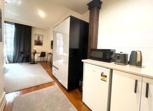a kitchen with white cabinets and a black refrigerator at Charming Studio Apartment in Auckland Central in Auckland