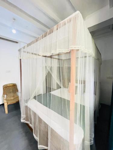 a bedroom with a bunk bed with white curtains at Double G Motel in Weligama