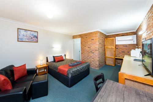 WondaiWondai Colonial Motel & Ivory's Restaurant的一间酒店房间，里面有一张床和一张沙发