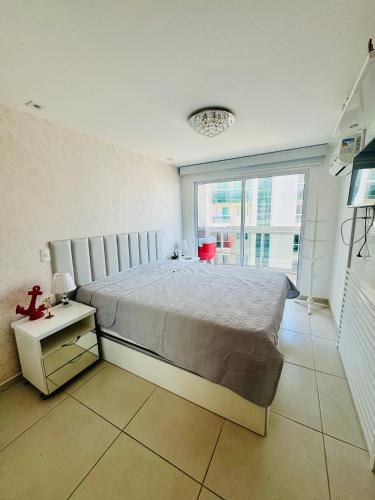 a bedroom with a large bed and a large window at Resort Praia Grande in Arraial do Cabo