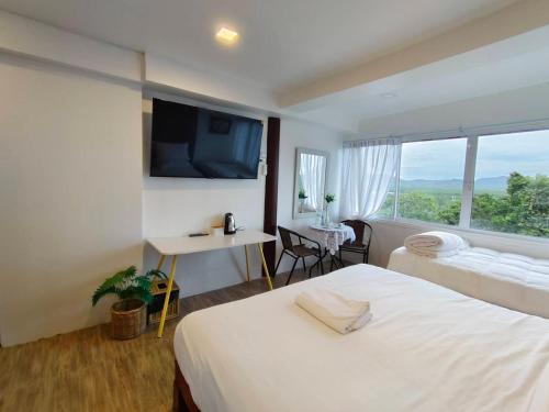 Un dormitorio con una cama y un escritorio y una ventana. en BaanPhutawanLanta, en Ban Mo Nae