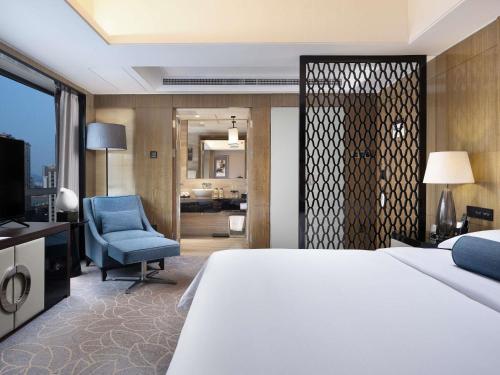 een slaapkamer met een groot bed en een blauwe stoel bij Pullman Shanghai Jing'an in Shanghai