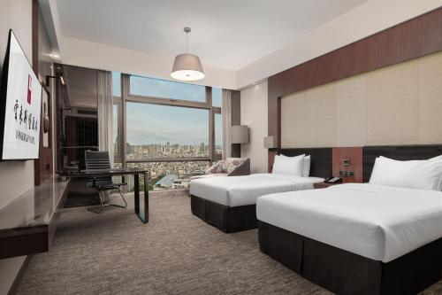 a hotel room with two beds and a desk at Vanburgh Hotel Guangzhou in Guangzhou
