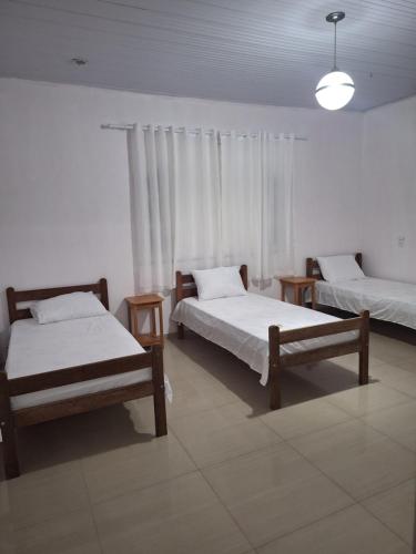 a room with two beds and a window with curtains at RR 2 Pousada e Restaurante in Manaus