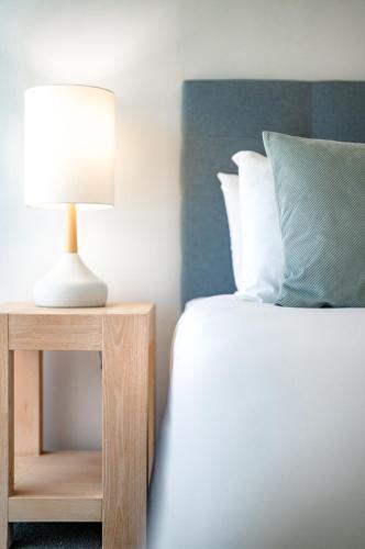a bed with a lamp on a night stand next to a bed at Sailport Mooloolaba Apartments in Mooloolaba