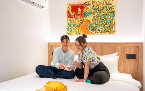 two women sitting on top of a bed at Lub d Bangkok Siam - New Look, Across from MBK & Skytrain Access in Bangkok