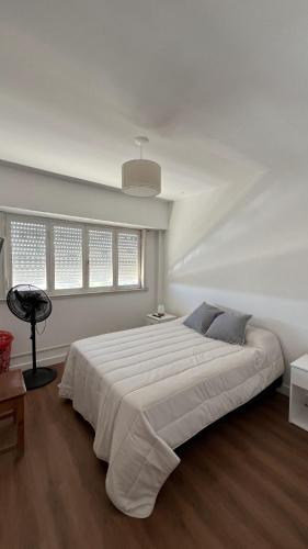 a white bedroom with a large white bed and windows at La gracie in San Bernardo