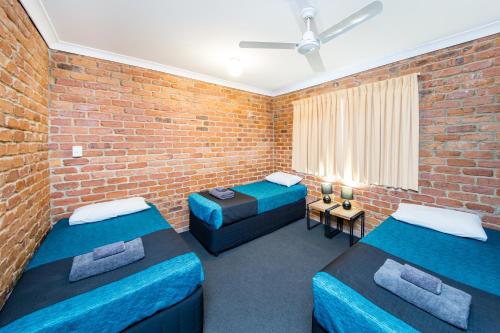 Una habitación con dos camas y una pared de ladrillo. en Wondai Colonial Motel & Ivory's Restaurant, en Wondai