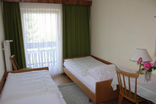 a bedroom with two beds and a table and a window at Dreimäderlhaus in Velden am Wörthersee