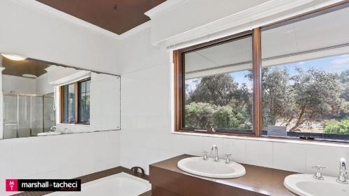 a bathroom with two sinks and a large window at Art House - 4 Bedroom in Barragga Bay