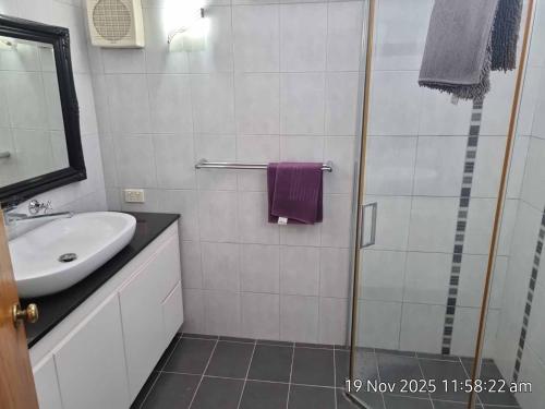 a white bathroom with a sink and a shower at Angel Apartment in Perth