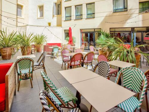 Un patio al aire libre con mesas, sillas y plantas. en ibis Styles Montpellier Centre Comedie, en Montpellier
