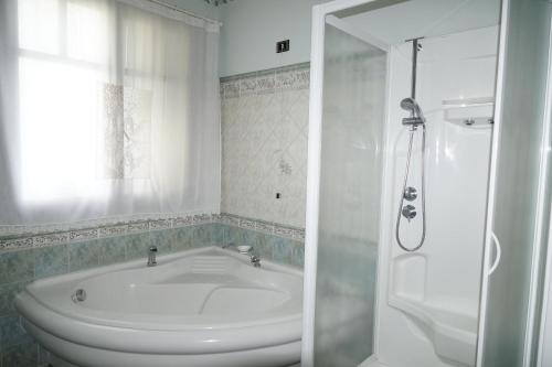 La salle de bains blanche est pourvue d'une baignoire et d'une douche. dans l'établissement Villa del Sole, à Zafferana Etnea