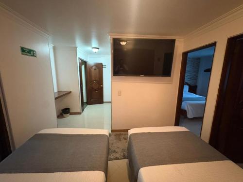 a bedroom with two beds and a flat screen tv at Lavid Hotel Palacio Real in Bogotá