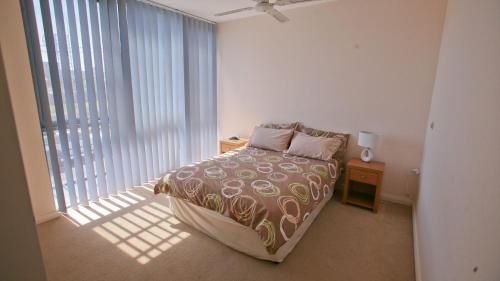 伯马吉Beach Pad Unit1, 2 Wallaga Street, Bermagui的一间卧室，里面有一张床和一扇大窗户。