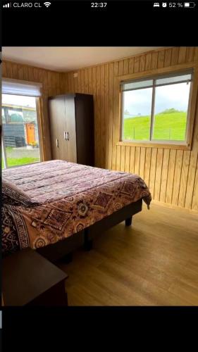 a bedroom with a bed in a room with two windows at Cabaña Licarayén in Puerto Varas
