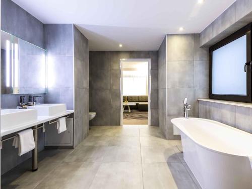 a bathroom with two sinks and a tub and a window at Novotel Wrocław Centrum in Wrocław