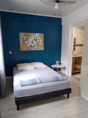 a bedroom with a bed with a blue wall at Ti case Les Girofles in Saint-Benoît