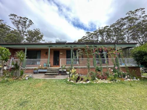 a brick house with a porch and a yard at Macyland in Woollamia