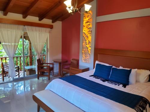 a bedroom with a large bed with blue pillows at Hotel & Spa Quinta Sauz in Tacámbaro de Codallos